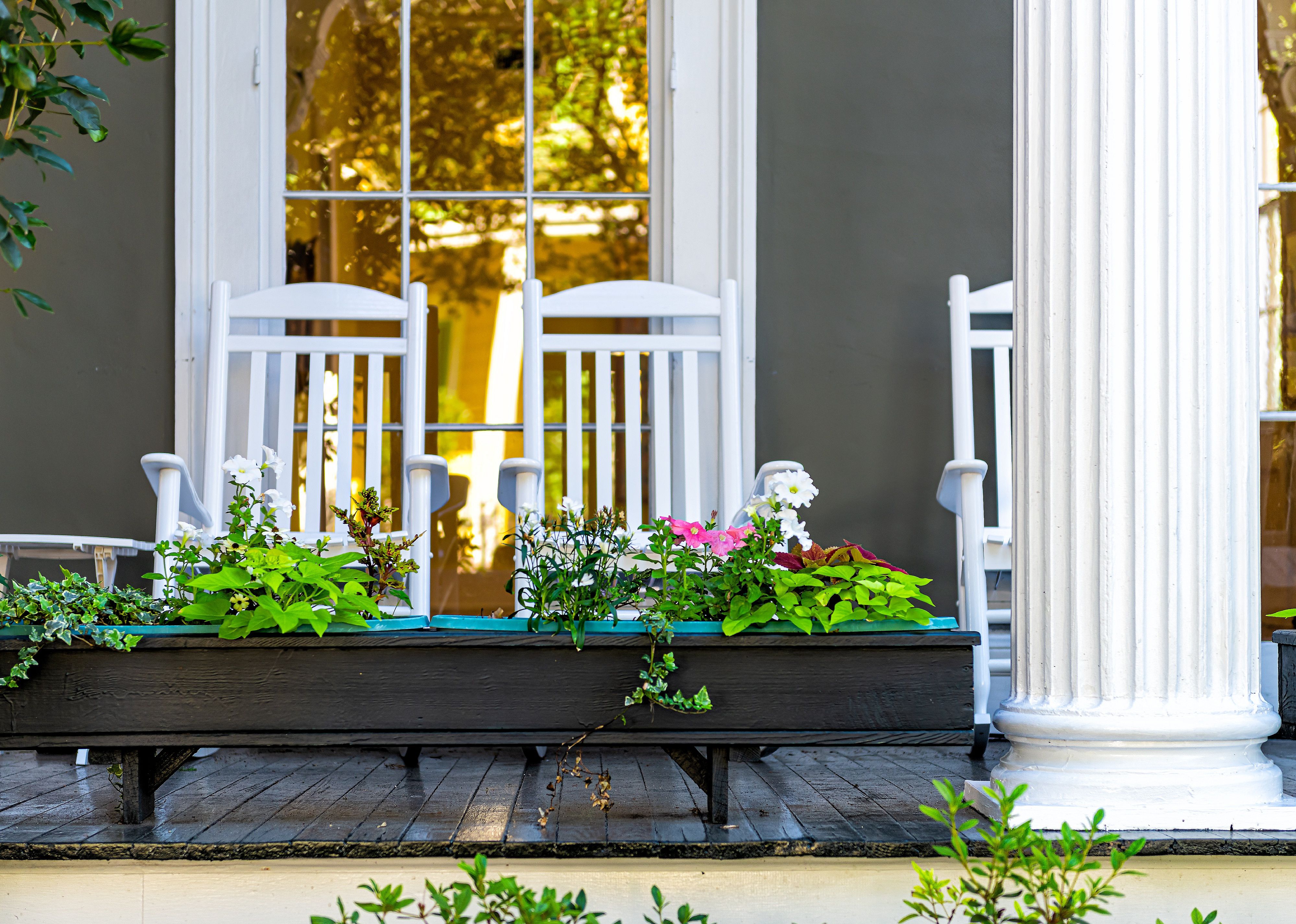 Detailed view of flower boxes and rocking chairs on porch.
