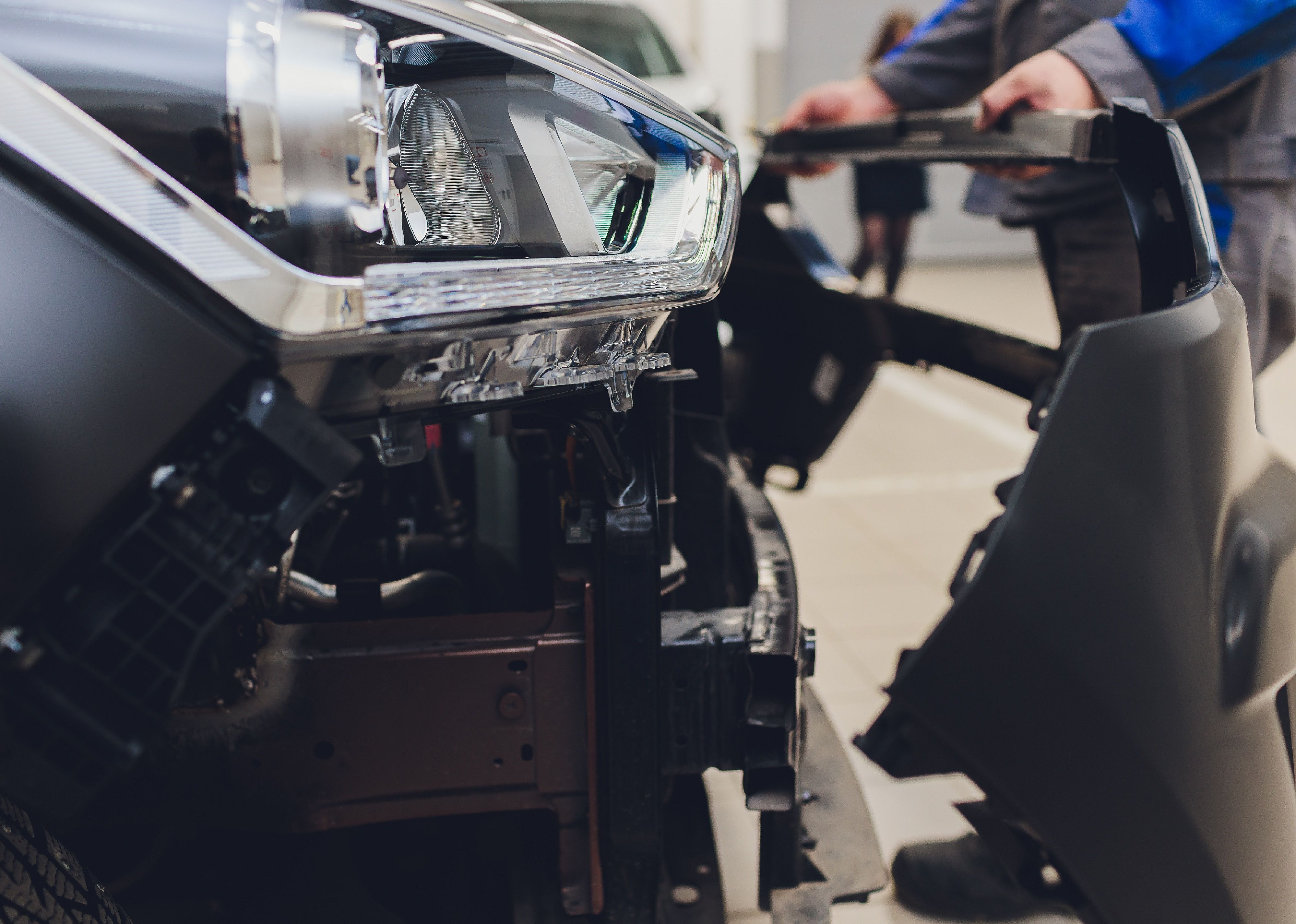 Man replacing bumper on a car.
