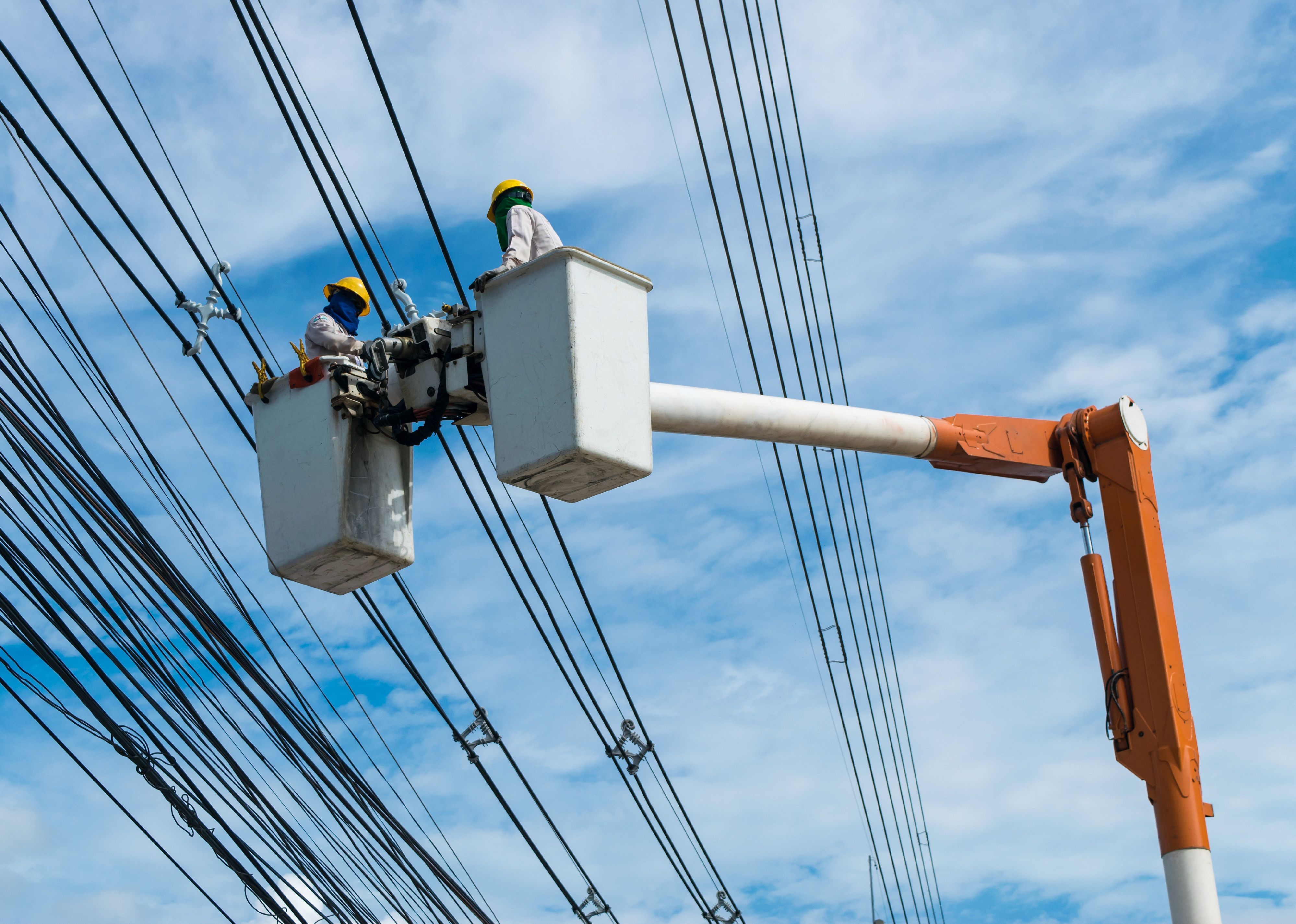 Electricians wiring cable to install and repair power lines.