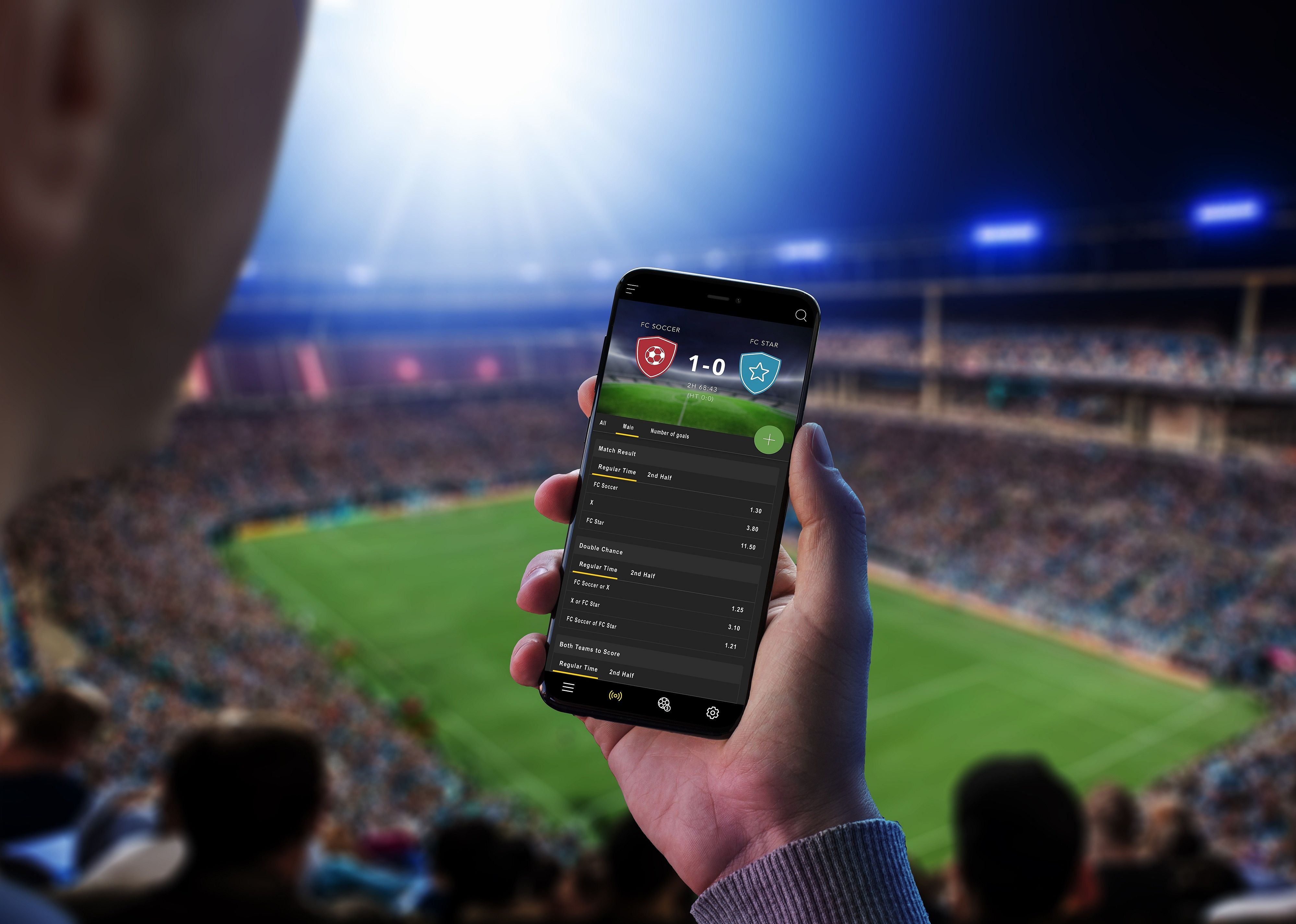 Man at a football match follows the odds and the current score.