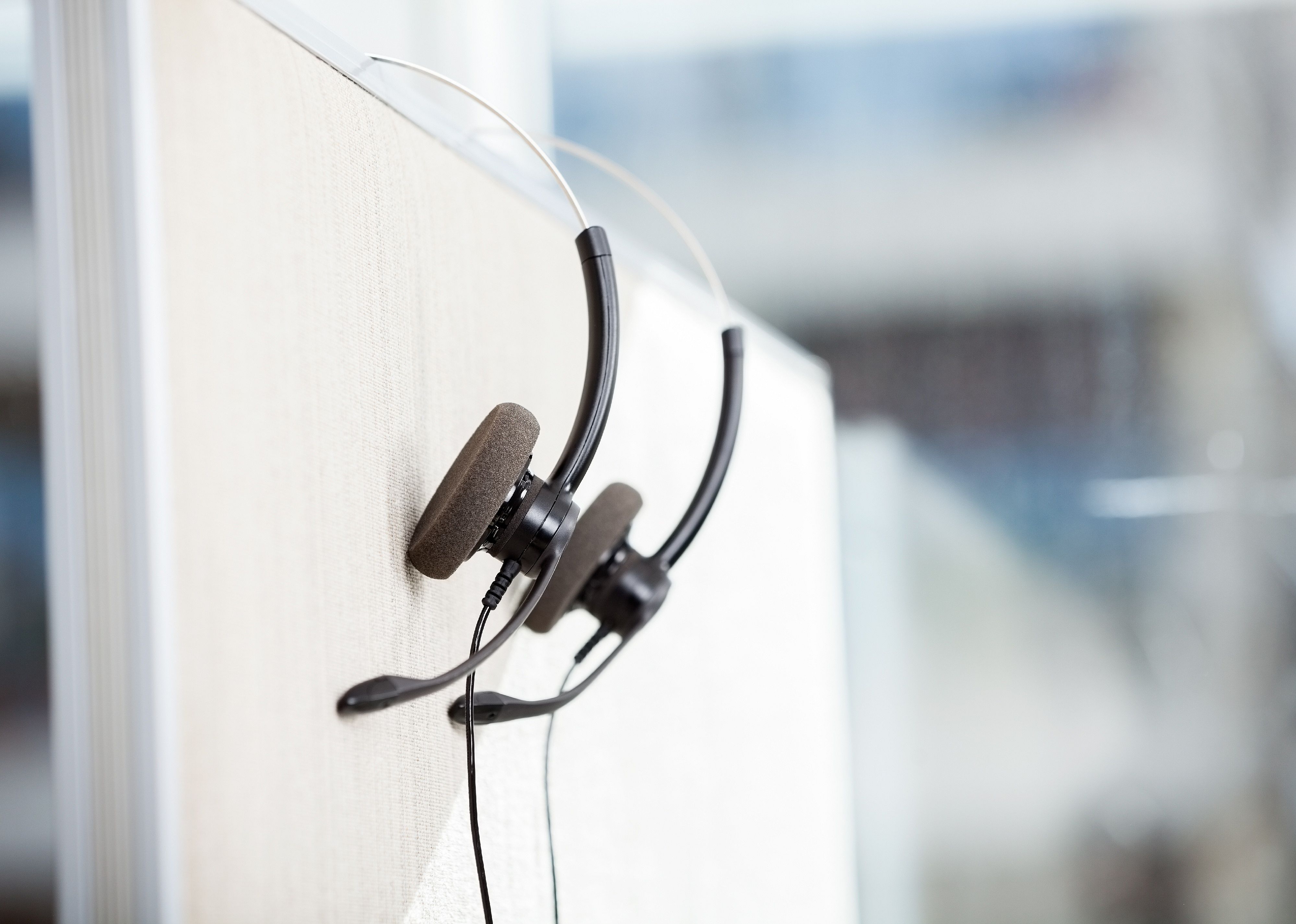 Headphones hanging on cubicle partition in empty office.