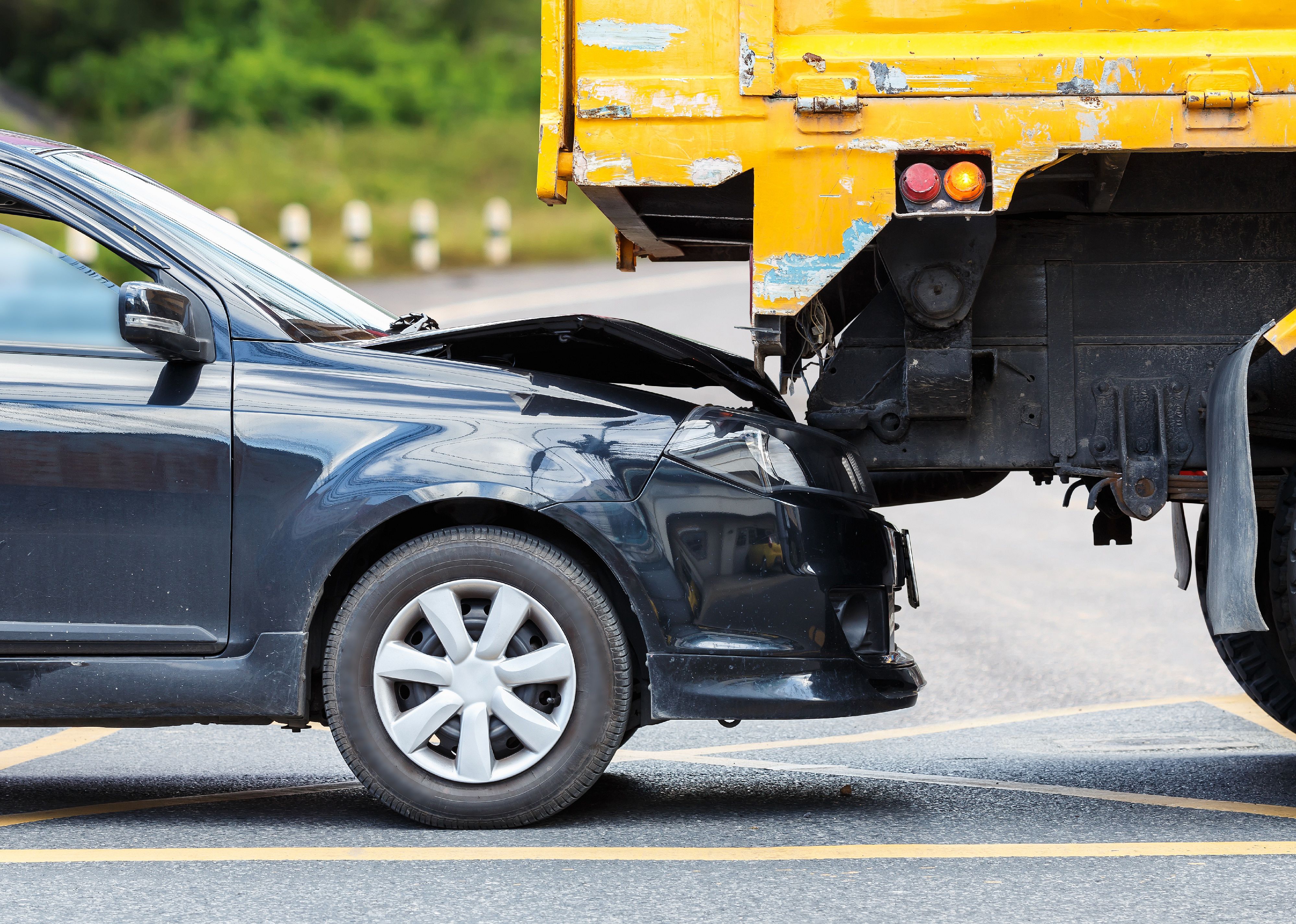 Accident on a road involving black car and yellow truck