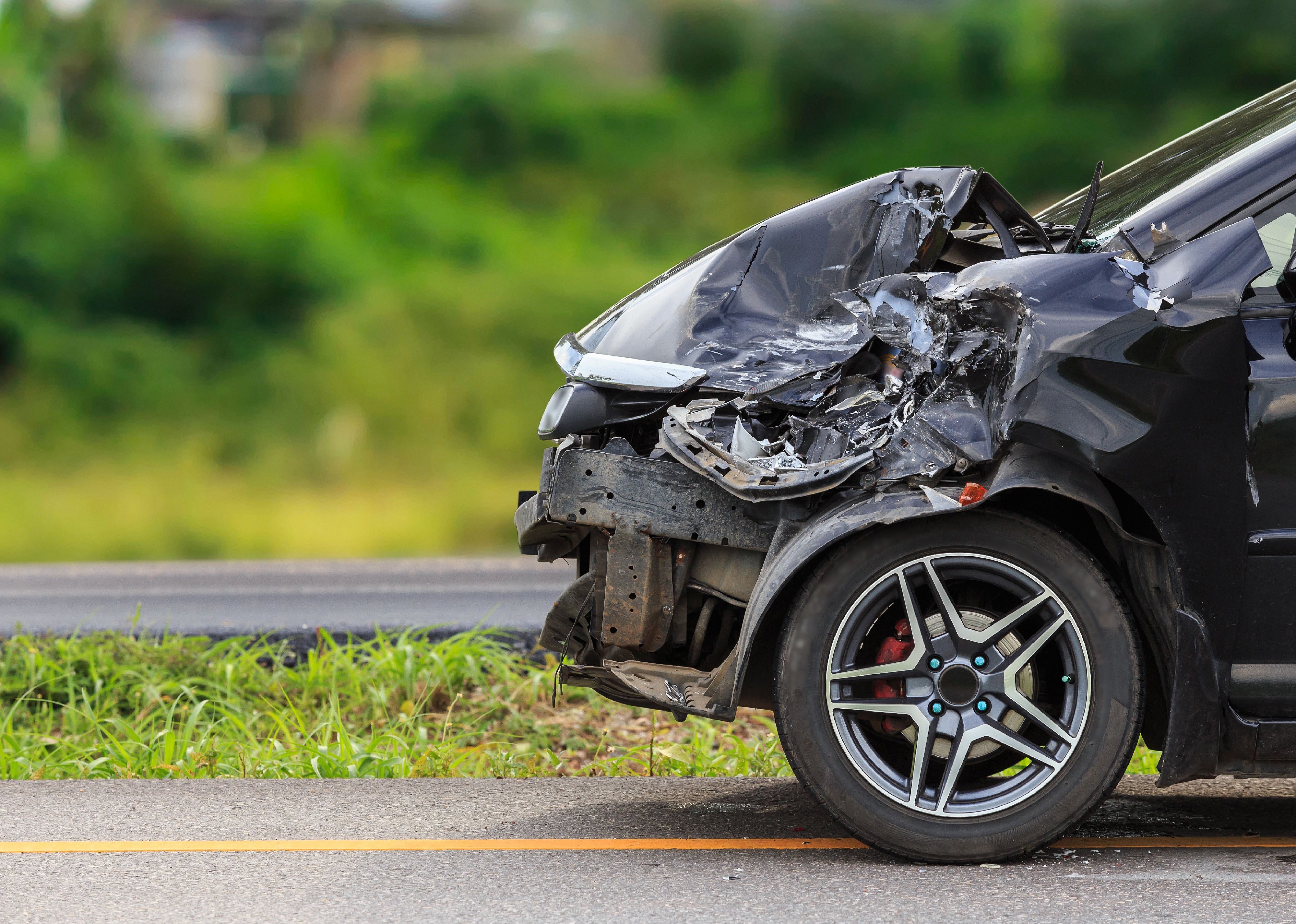 Front of black car damaged by an accident on the road