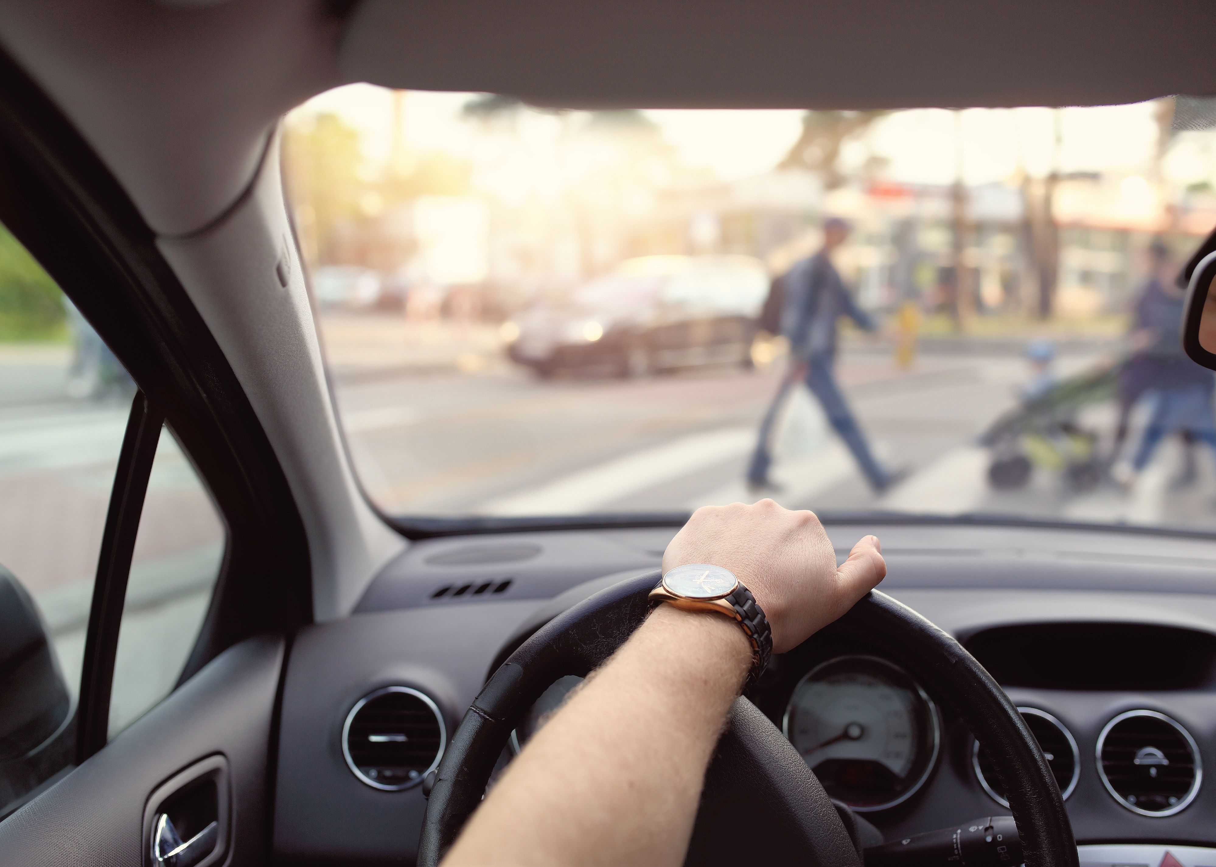 Driver with hand on wheel and pedestrians in front