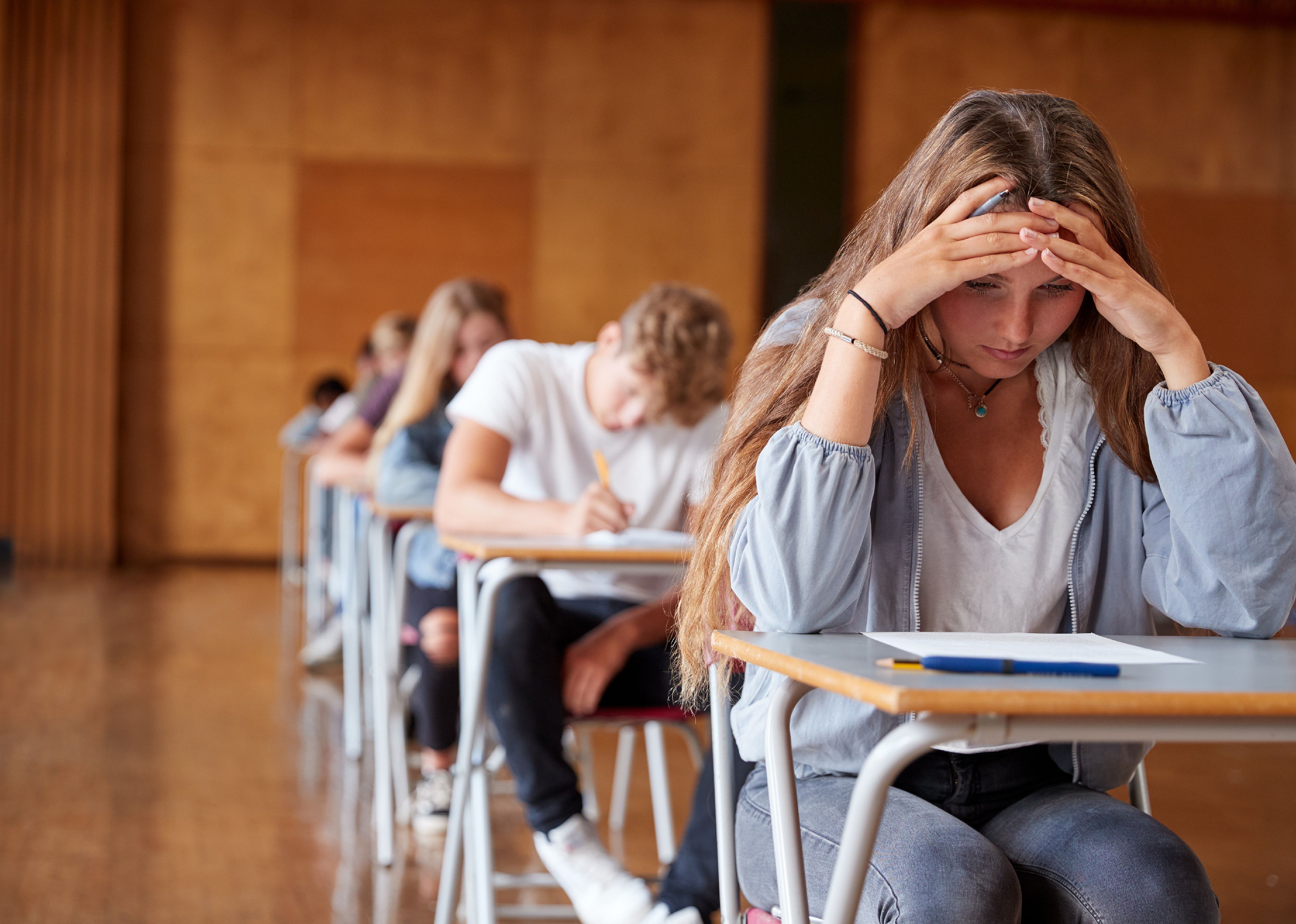Teens sitting at desks in a row.
