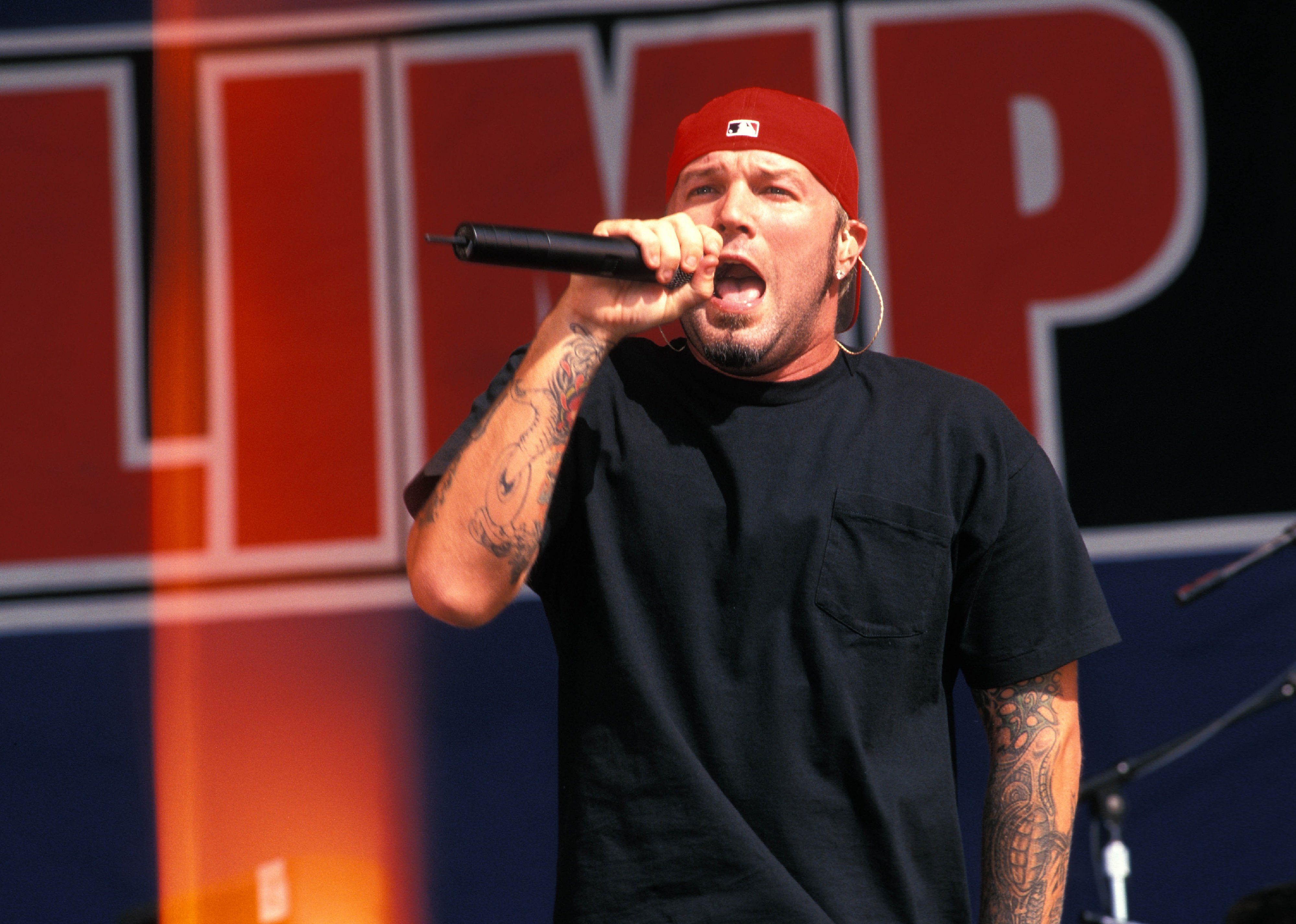 Limp Bizkit performing in a red backwards ballcap.