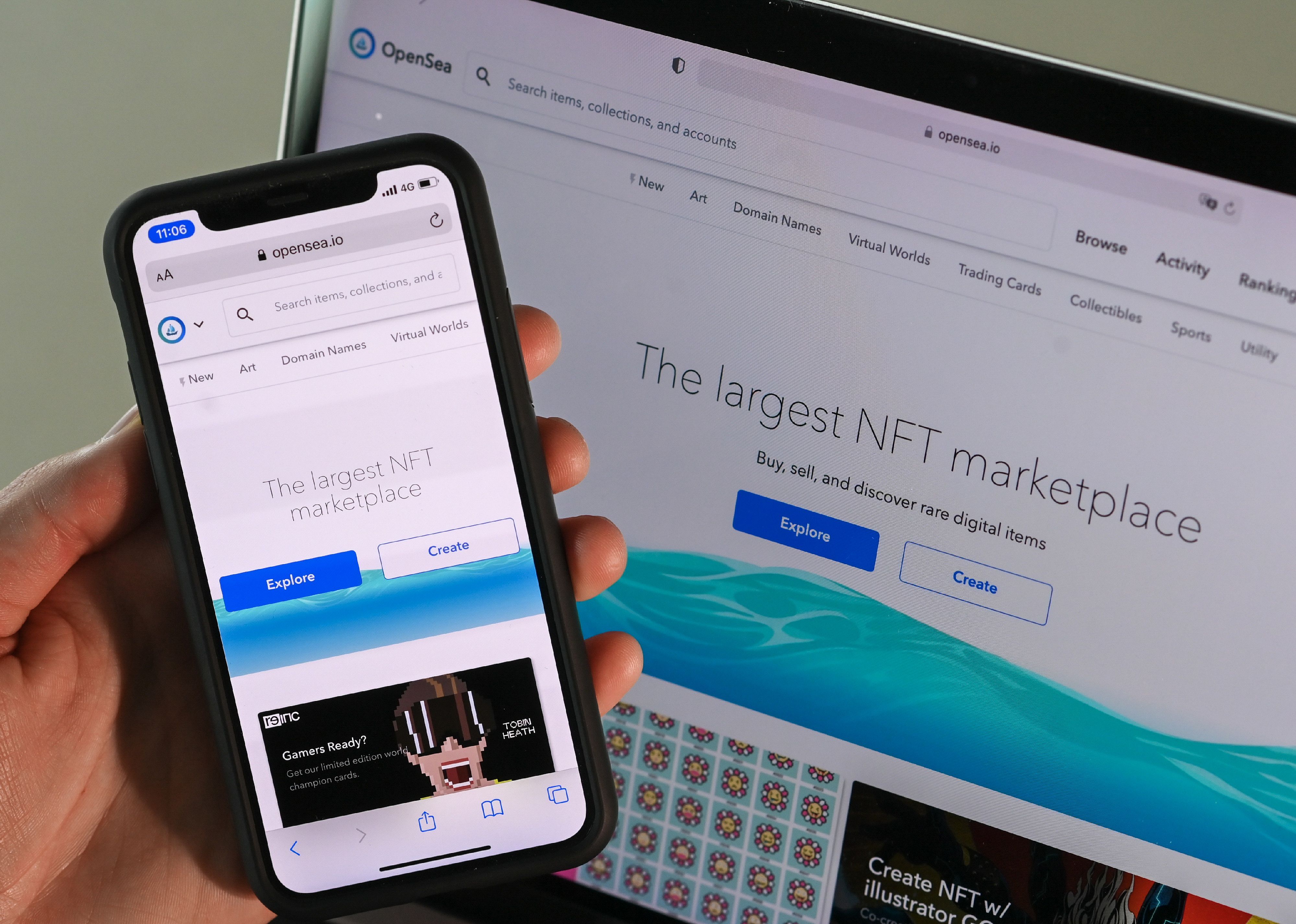The OpenSea app on a cellphone in front of a computer screen.