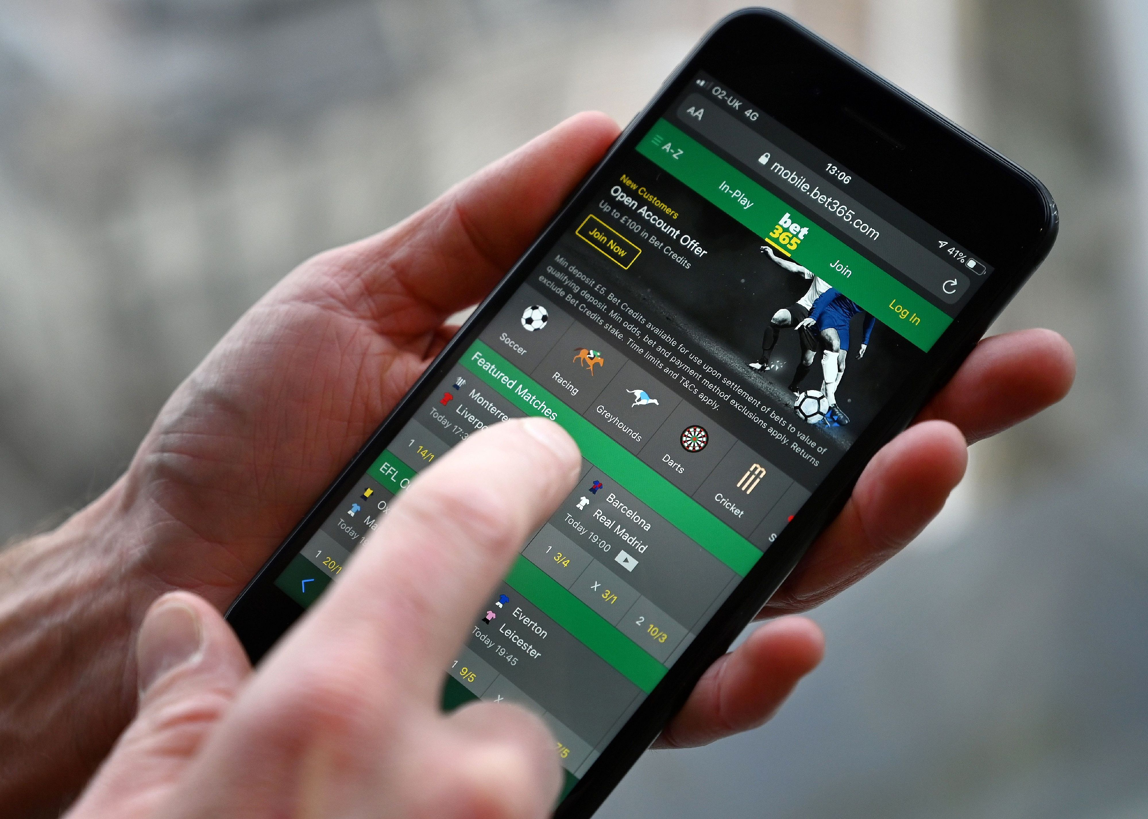 A man poses for a photograph with the online gambling website displayed on a smartphone.