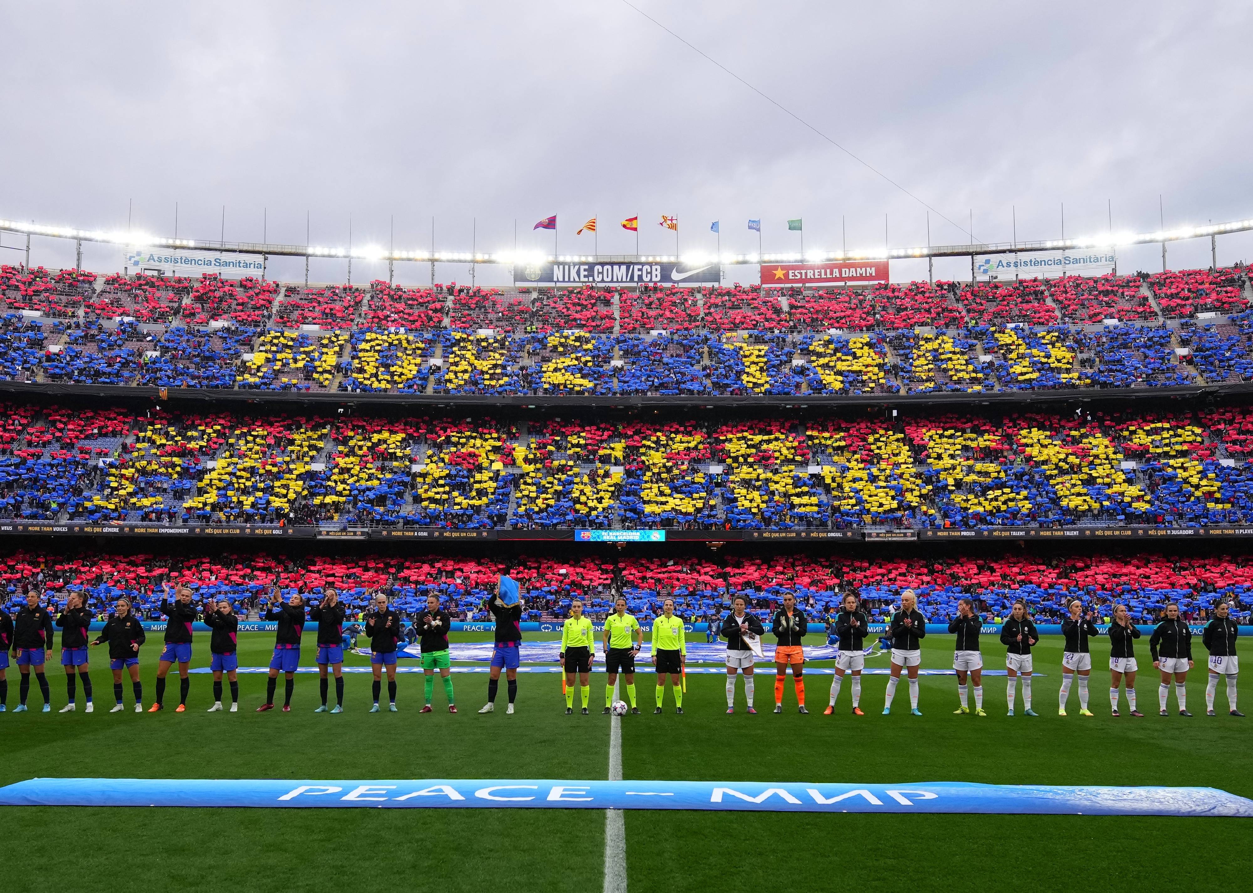 Players of FC Barcelona and Real Madrid line up as fans perform a tifo in the stands 