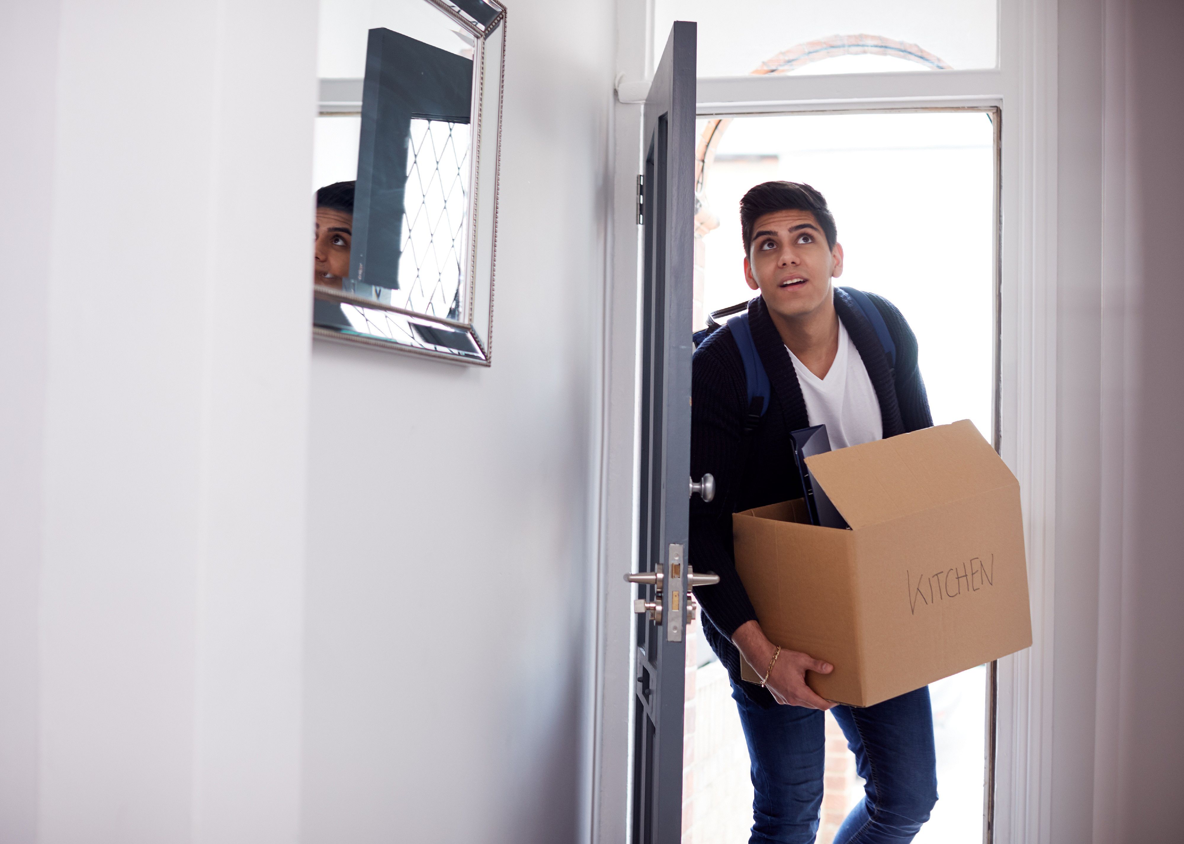 Young man entering room carrying a cardboard box