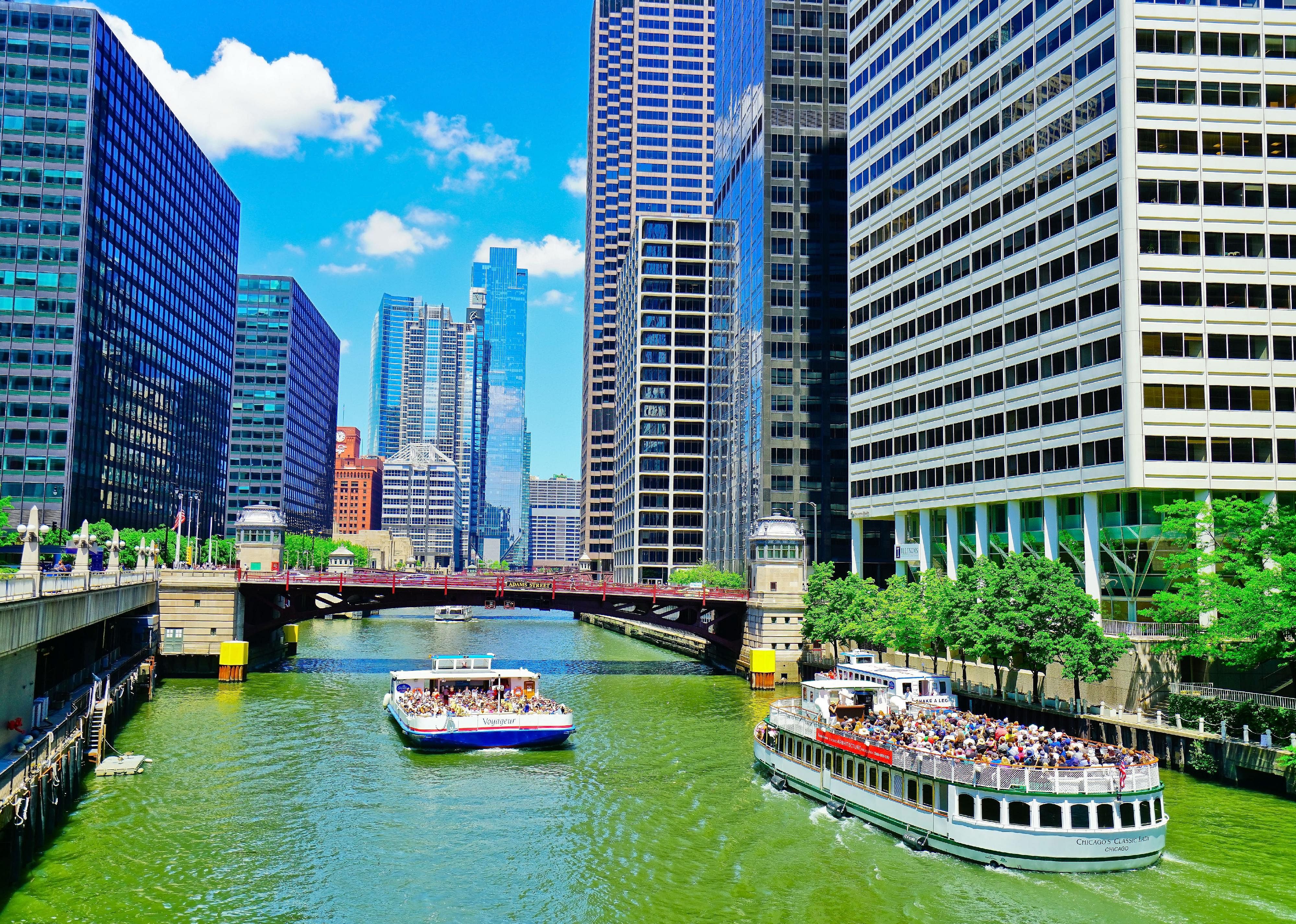 Two boats filled with people enjoy a day on the Chicago River.