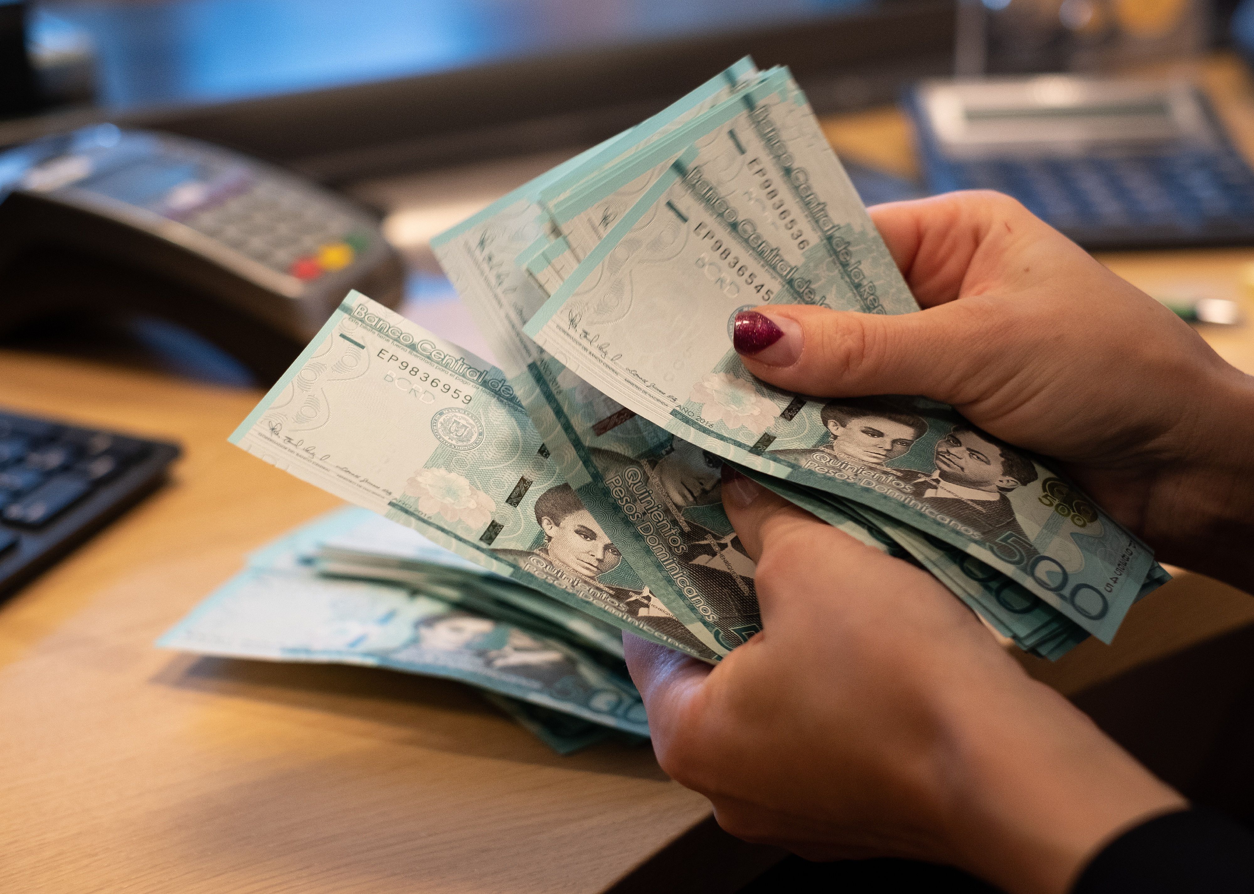 Cashier counting Dominican Republic 500 peso bank notes.