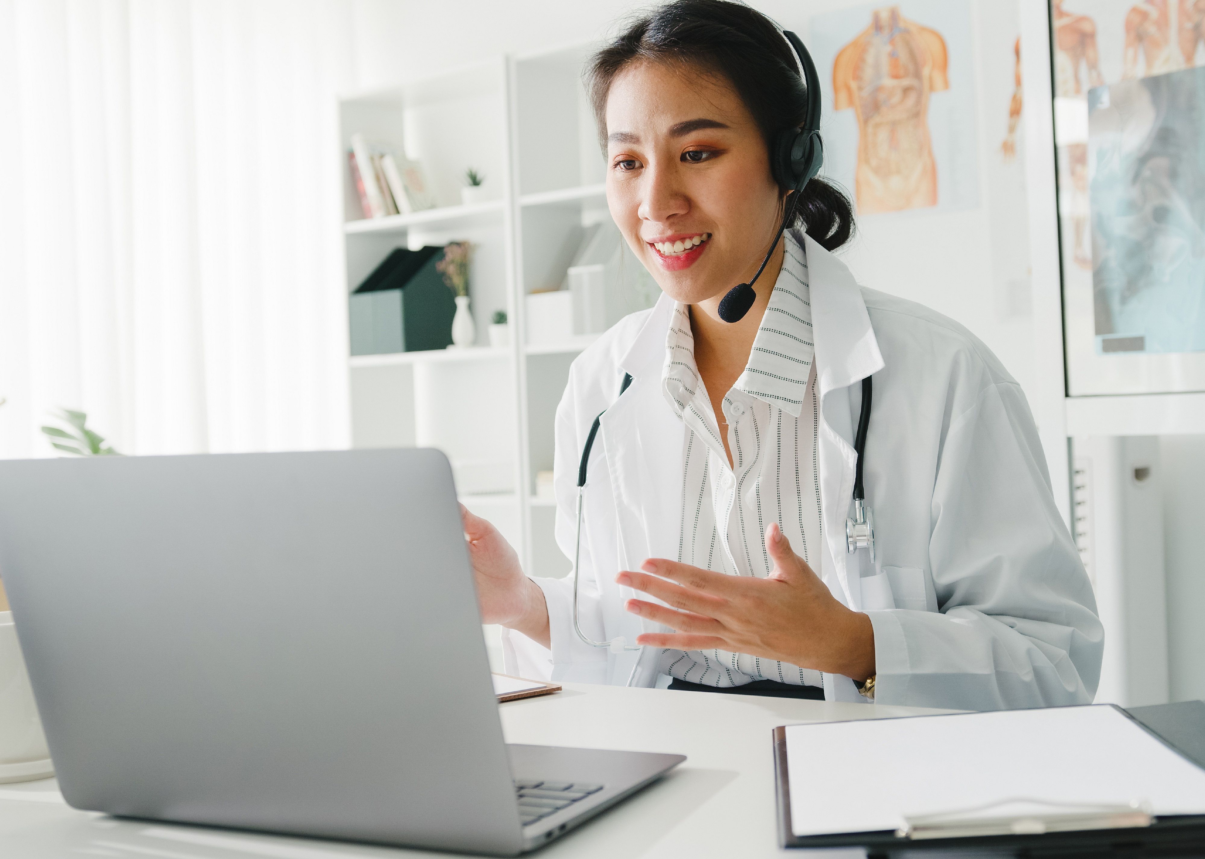 Young female doctor with stethoscope on video call with a patient
