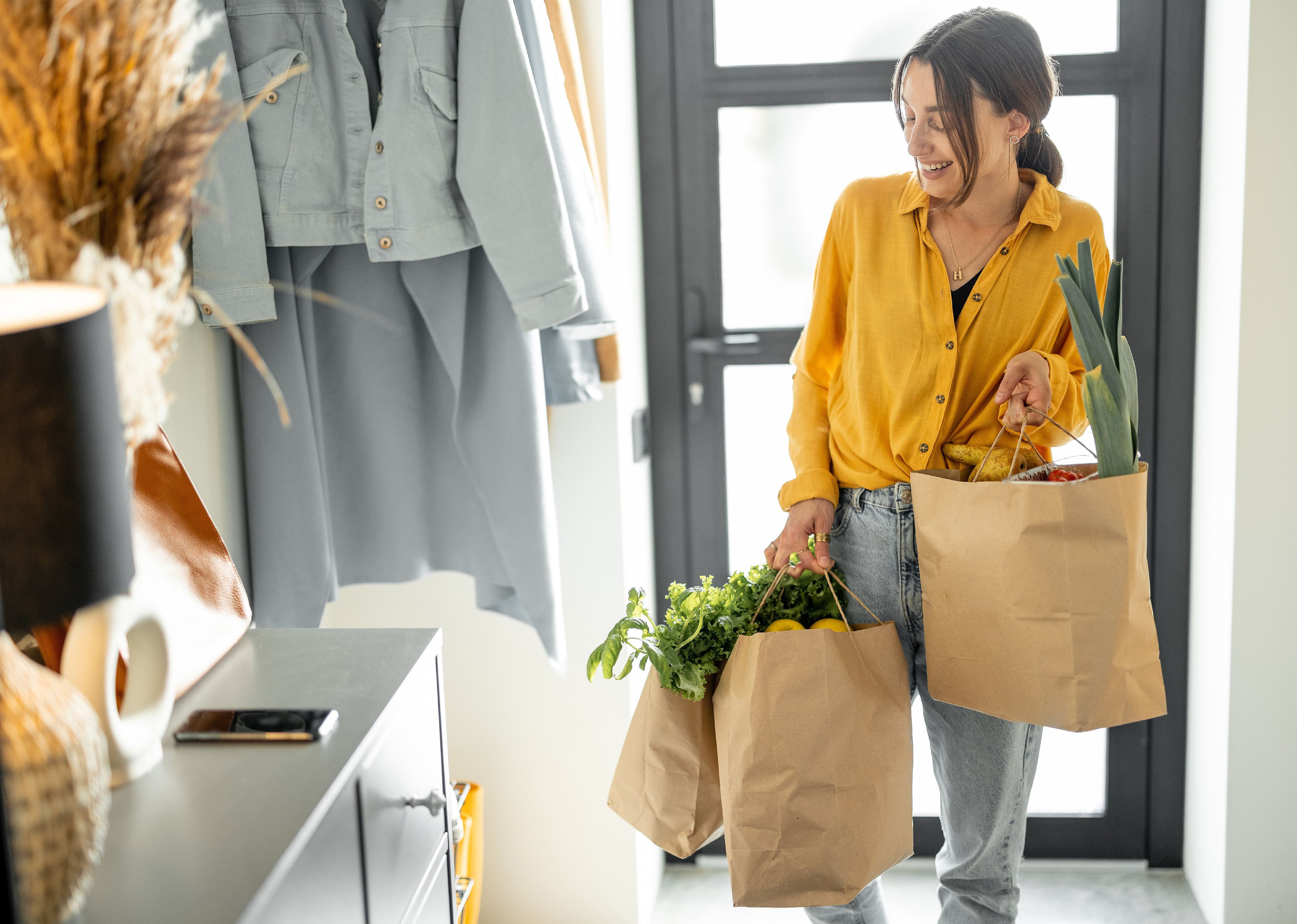 Woman coming home with bags full of fresh groceries.