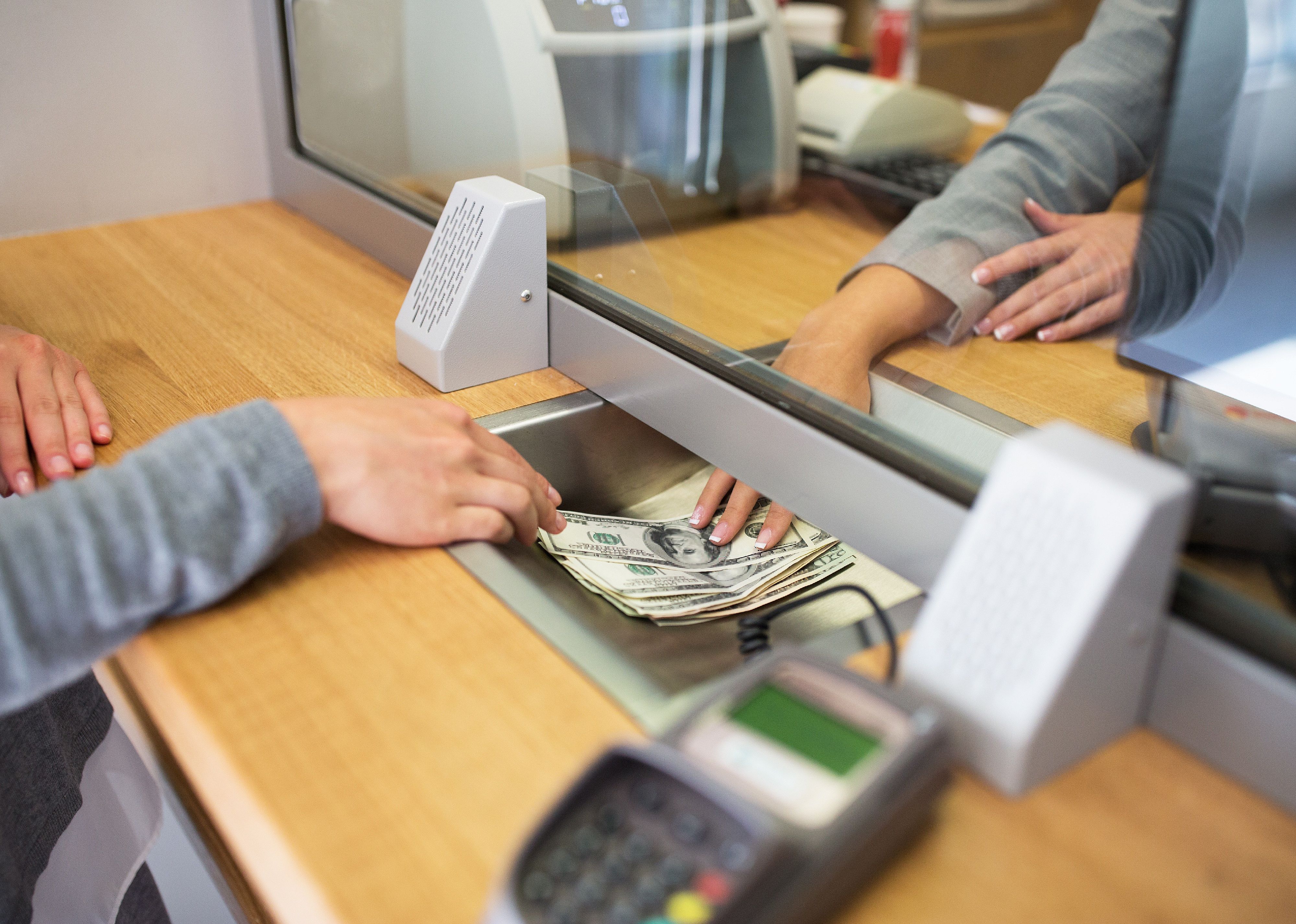 Clerk giving cash to customer at bank office.