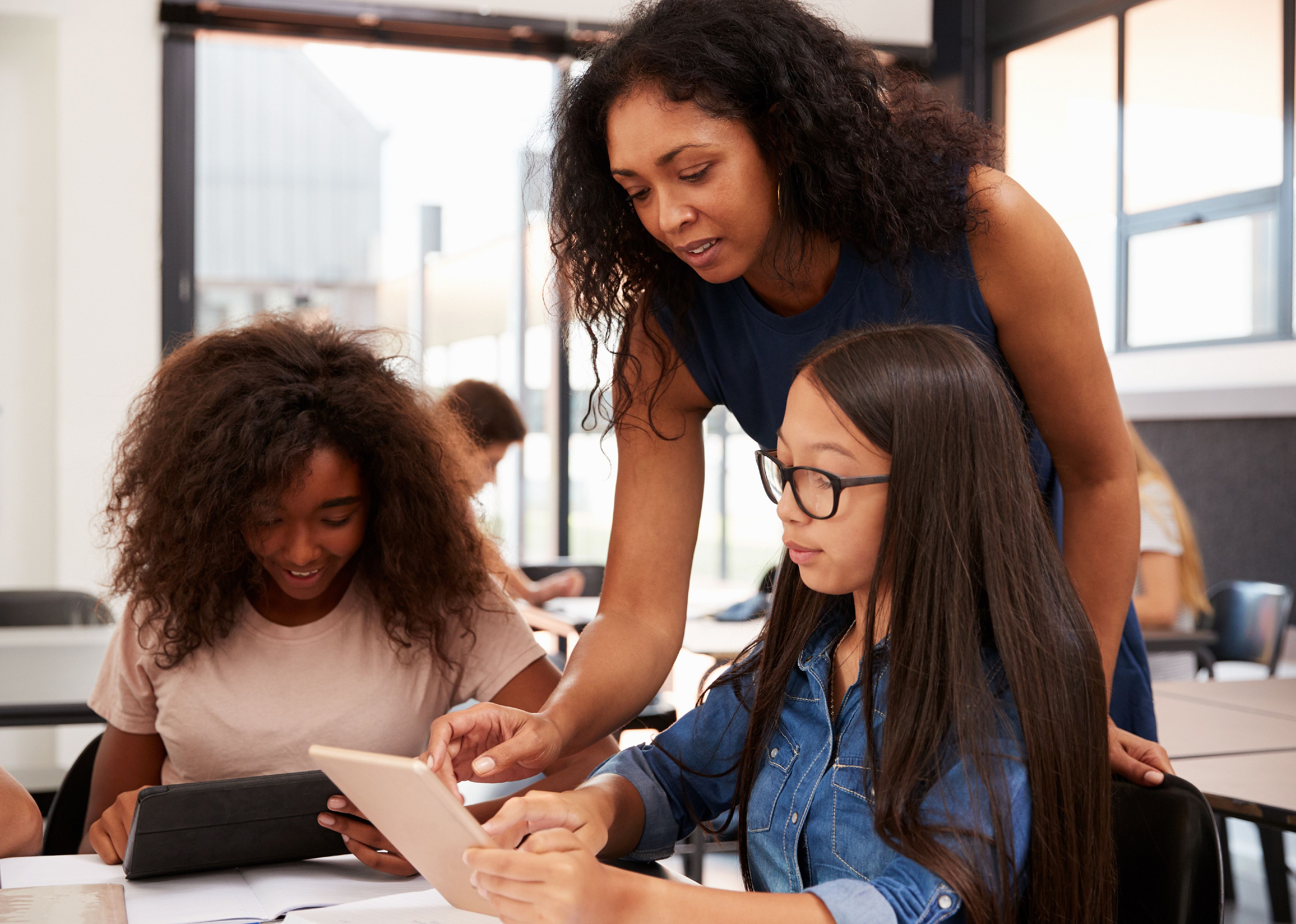 Teacher helping high school students with technology.