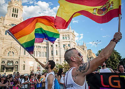 A man waves the Spanish flag and another the LGTBI+ flag in front of the Palacio de Cibeles, during the Pride March in Madrid.