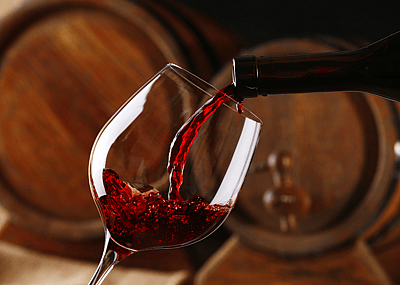 Close up pouring wine with casks in background