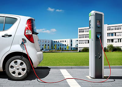Electric car on charging spot in front of office buildings.