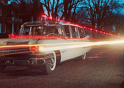 Light trails from a 1950s Cadillac ambulance driving on a road.