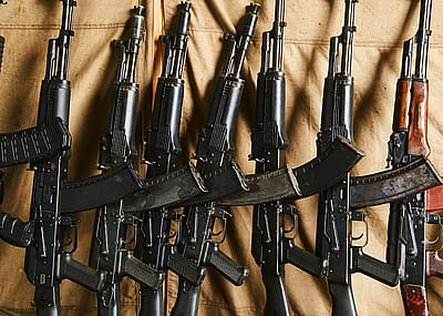 AK 47 assault rifles stand along the wall against a tarp.