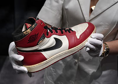 Gloved hands holding an original Air Jordan 1 at an auction at Christies.