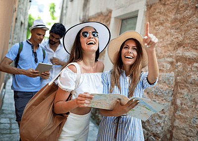 A group of friends consulting a guide book and walking down a narrow road while on vacation
