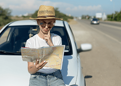 A woman reads a roadmap by the side of the road.