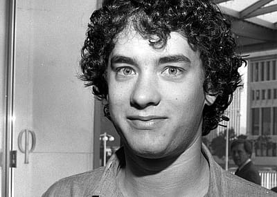 A curly-haired Tom Hanks photographed in the 1980s.