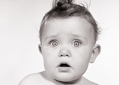 Wide-eyed baby from the 1950s looking at the camera.