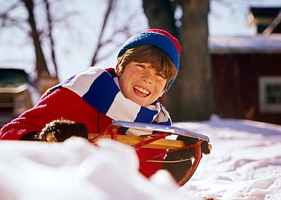 Smiling child sledding in the winter in the 1960s or '70s.