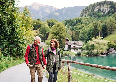 Senior couple hiking near a lake, holding hands, and enjoying the outdoors.