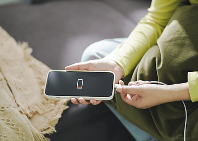 Person's hands plugging a low battery phone into a charger