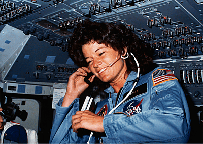 Astronaut Sally K. Ride, STS-7 mission specialist, communicates with ground controllers from the flight deck of the Earth-orbiting Space Shuttle Challenger, circa 1983.
