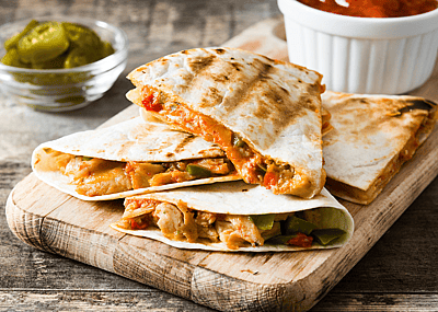 Mexican quesadilla with chicken, cheese and peppers on a wooden table.