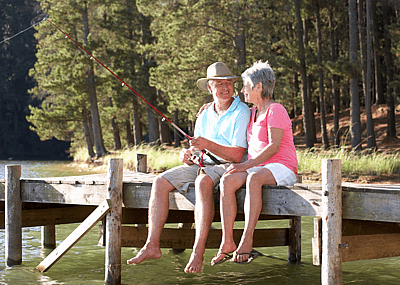 Senior couple sitting on a lakeside dock and fishing
