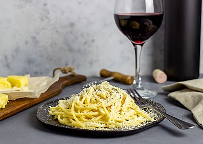 Roman pasta spaghetti cacio e pepe with black pepper, cheese, and wine.