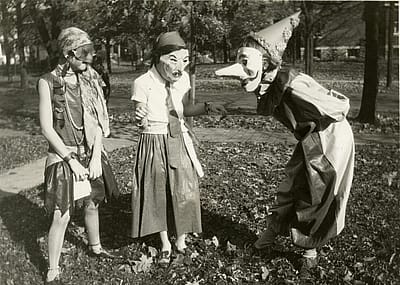 Three girls amuse each other with their masked costumes as they prepare for Halloween festivities in the College Hill neighborhood of Cincinnati, Ohio, 1929.