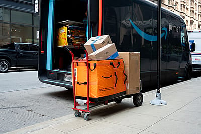Amazon packages on a hand truck next to an electric Amazon delivery truck in Chicago.