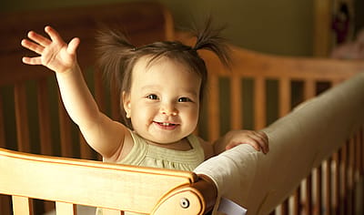 Baby girl in a crib waving