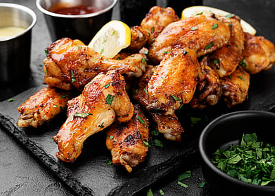 Baked chicken wings served with different sauces and lemon slices