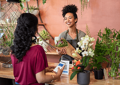 A florist handing flowers to a customer who has just scanned a QR code.