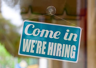 A come in we're hiring sign outside a door.