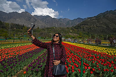 A woman taking a selfie in a field of flowers.