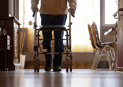 An elderly man using a walker in a nursing home.