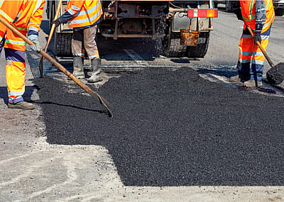 Road workers repairing a street with new hot asphalt