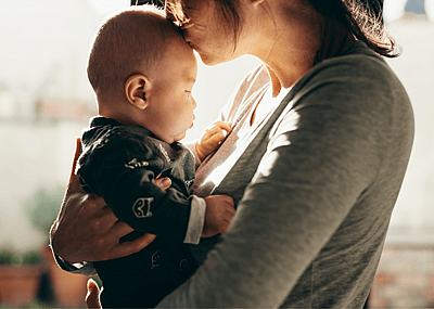 A parent kisses an infant on the head.