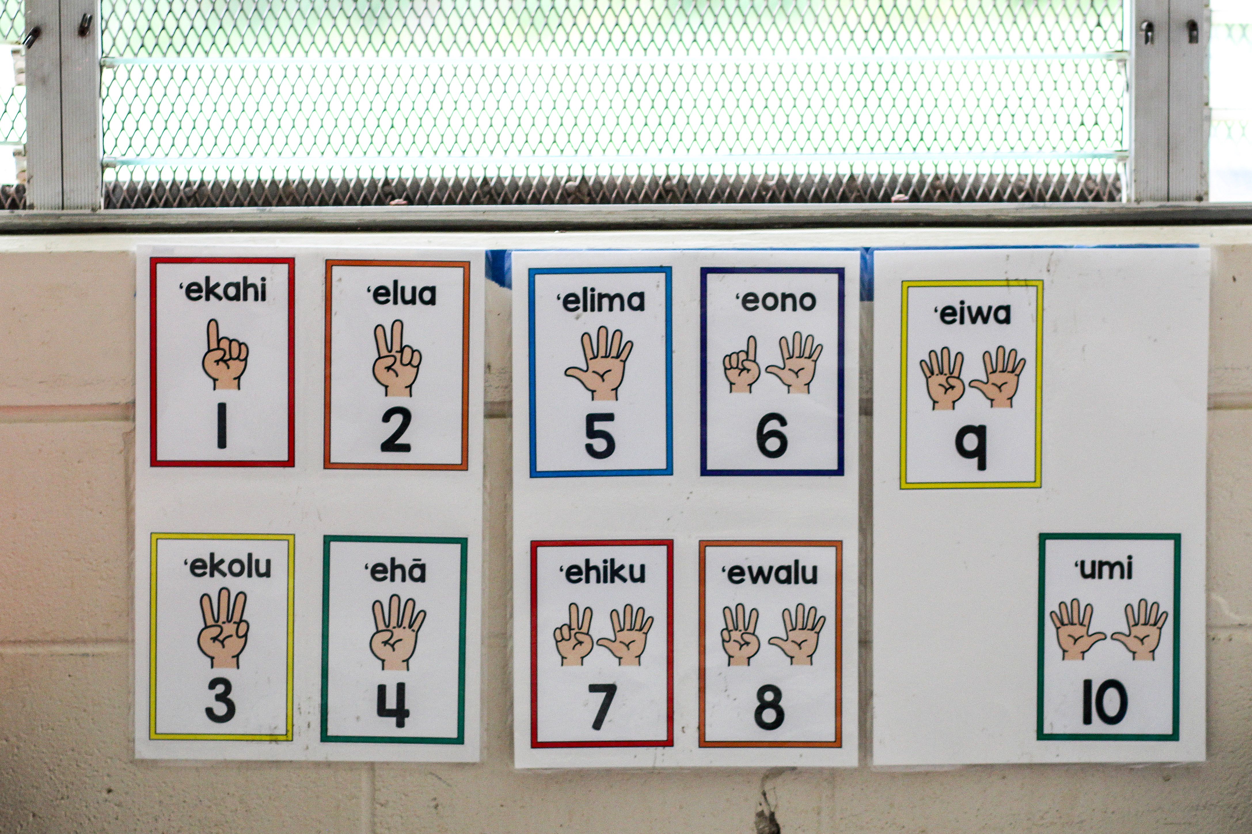 Laminated cards hung on a wall indicate the Hawaiian words for the numbers 1 through 10.
