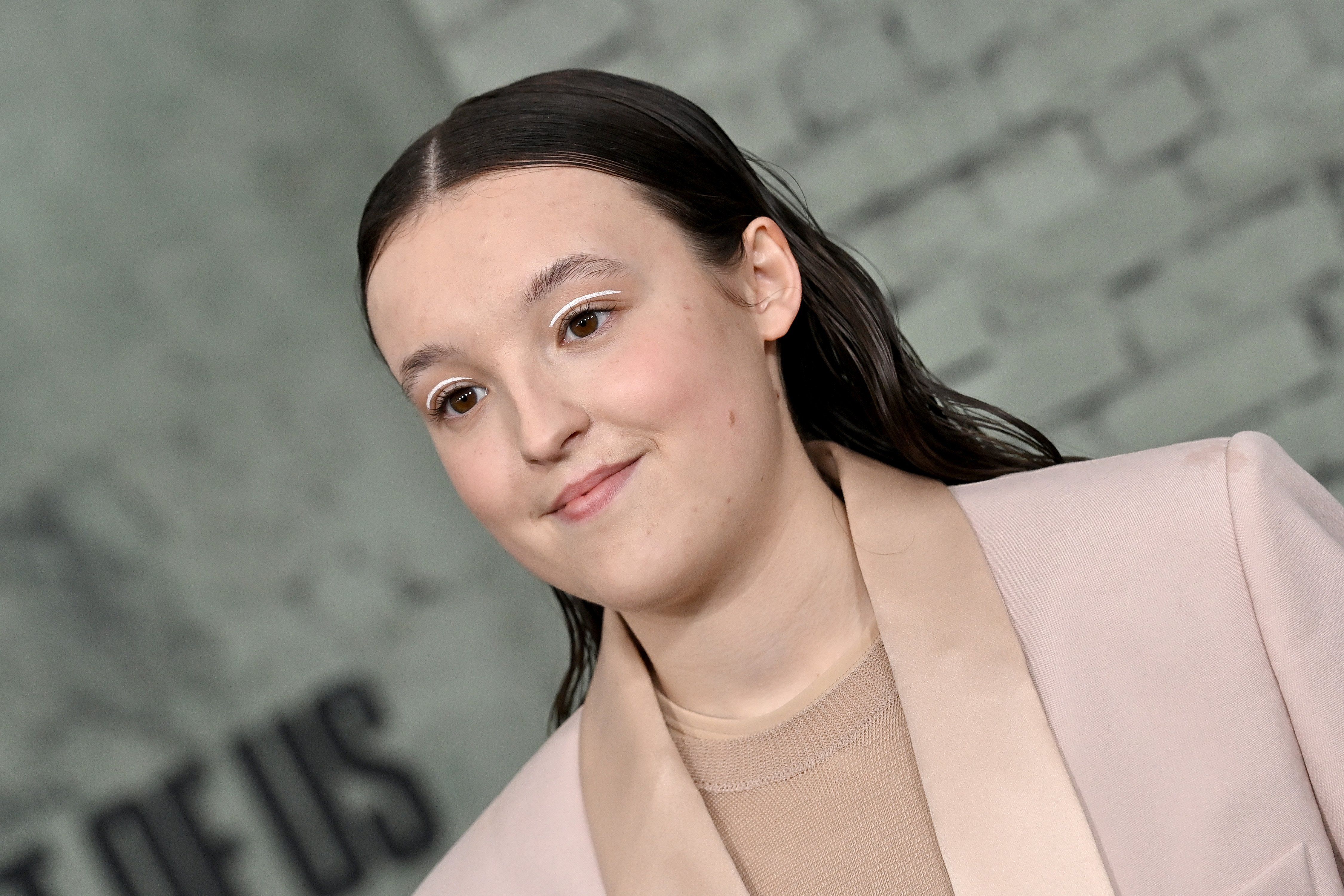 Bella Ramsey in a pale pink suit.