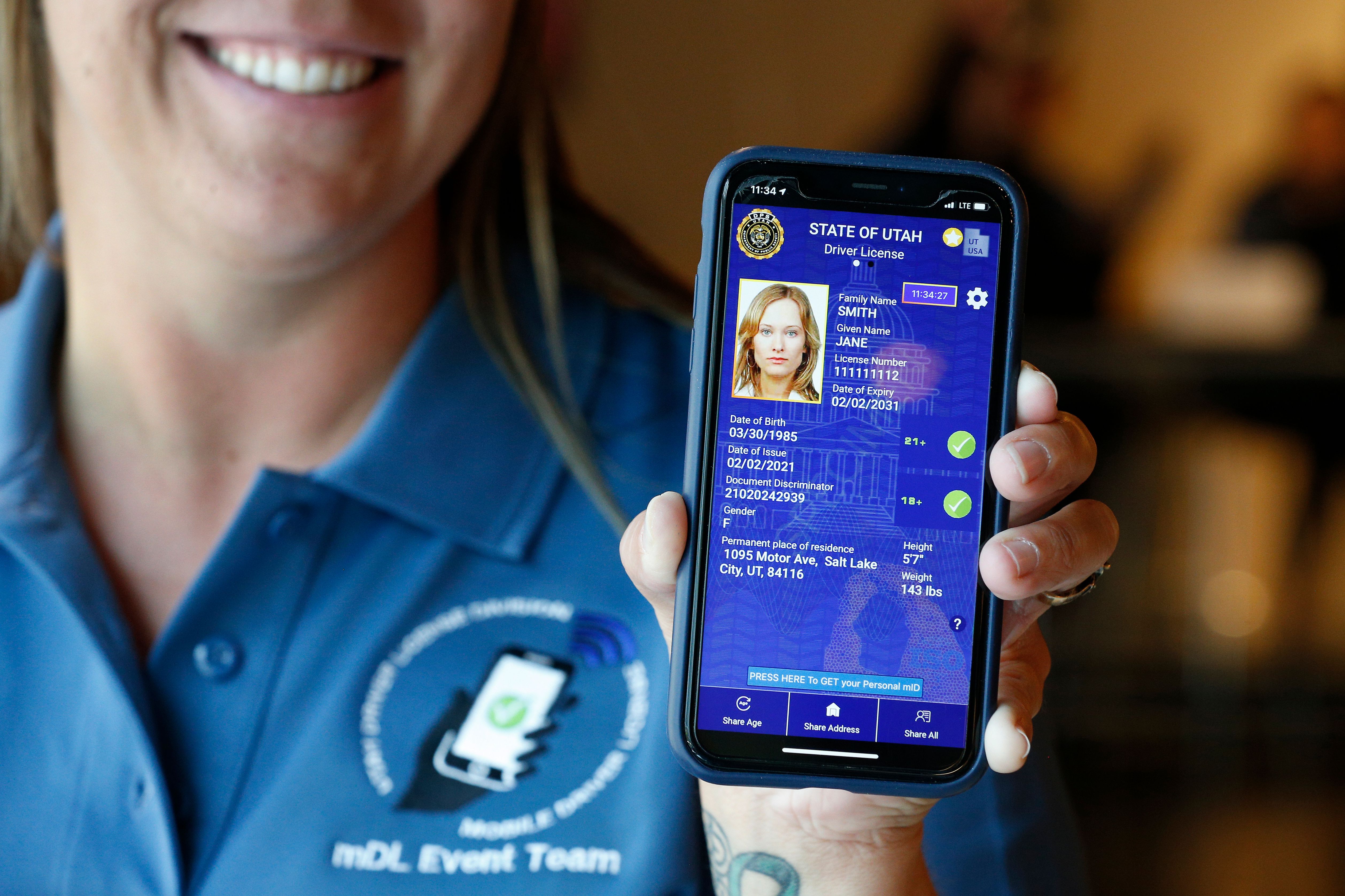 A person holding a smartphone with a mobile drivers license displayed.